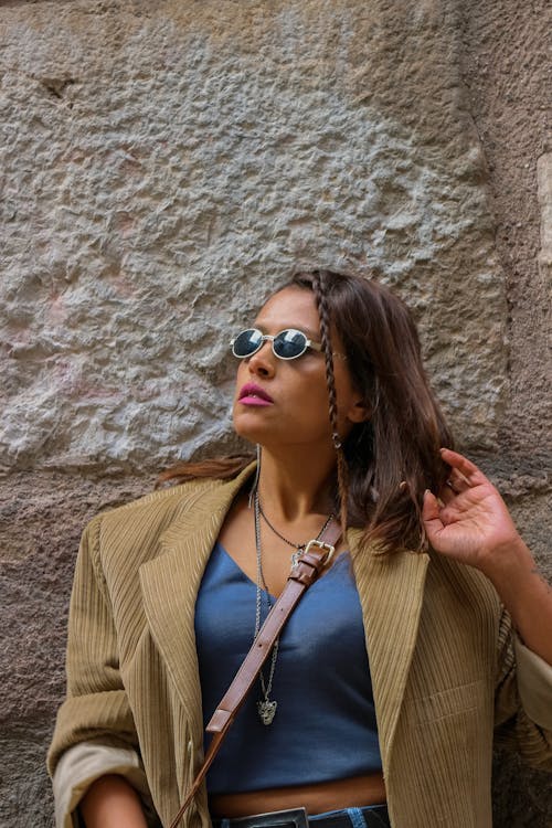 Woman in Brown Blazer and Sunglasses Leaning on a Wall