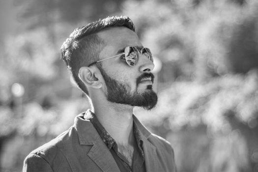 Black and white portrait of a stylish man outdoors wearing sunglasses.