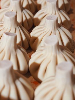 Close-up view of uncooked dumplings neatly arranged, highlighting their detailed folds and texture.