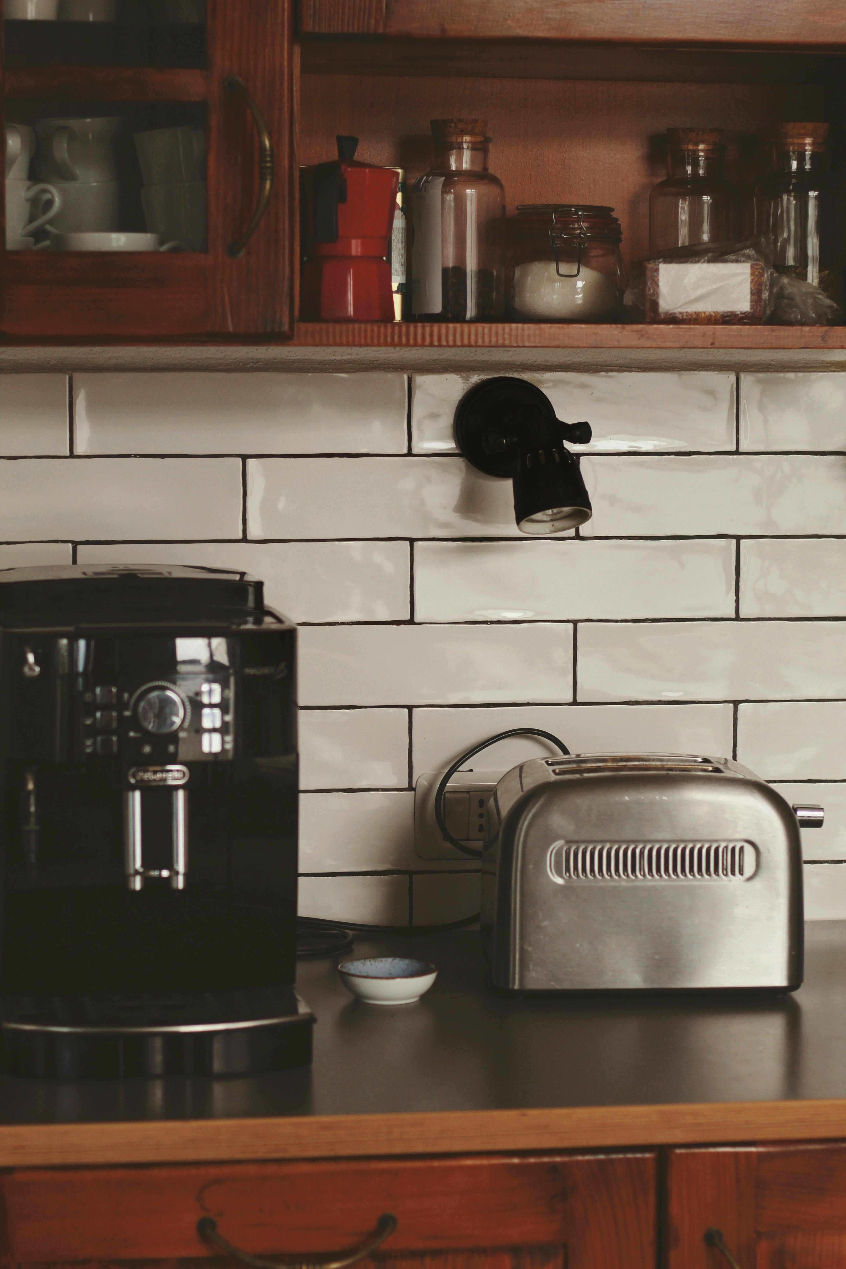 Electric kettle, coffee machine and toaster on kitchen counter near yellow  wall Stock Photo