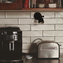 A toaster beside a coffee machine on a tiled kitchen worktop