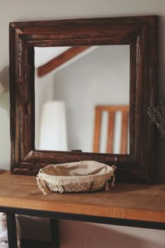 Cozy wooden mirror and table with a basket, reflecting a warm and rustic interior decor.