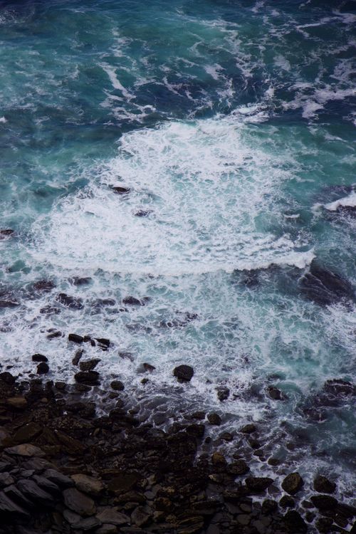 Free Dynamic aerial shot of ocean waves crashing over a rocky shore, showcasing nature's raw power. Stock Photo