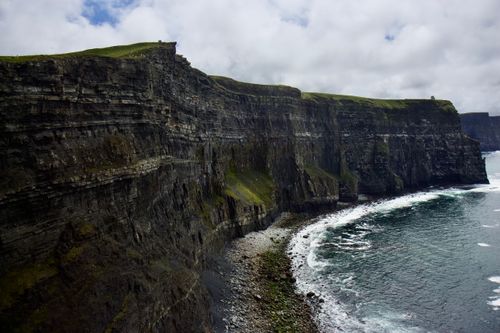 Free Scenic view of the Cliffs of Moher with rugged coastline and cloudy sky in Ireland. Stock Photo