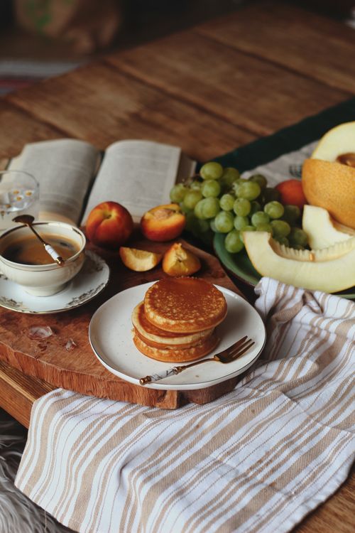 Free Cozy breakfast setup with pancakes, coffee, and fresh fruits on a wooden table. Stock Photo