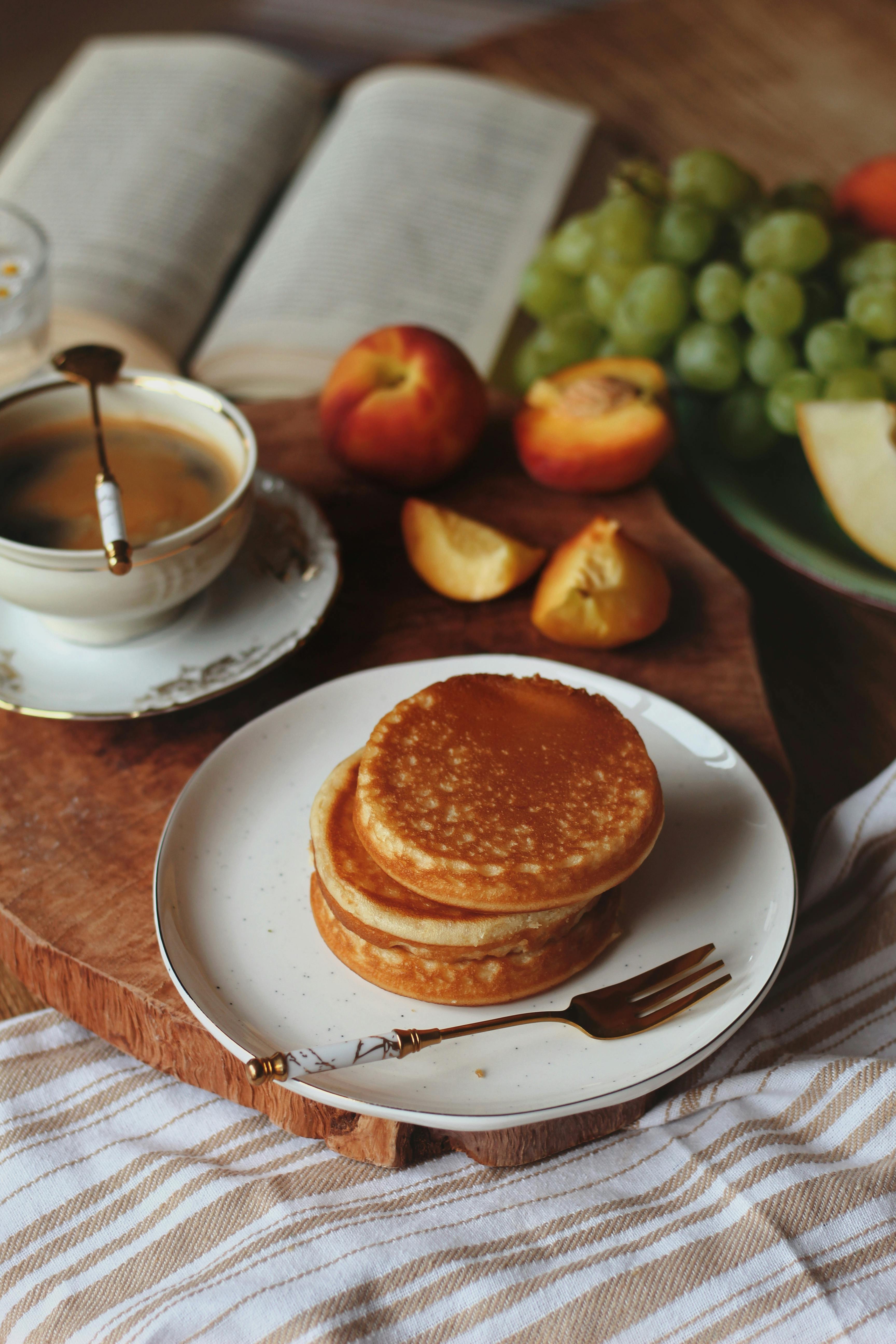 Stack of pancakes with coffee and fresh fruits on a cozy morning set-up.