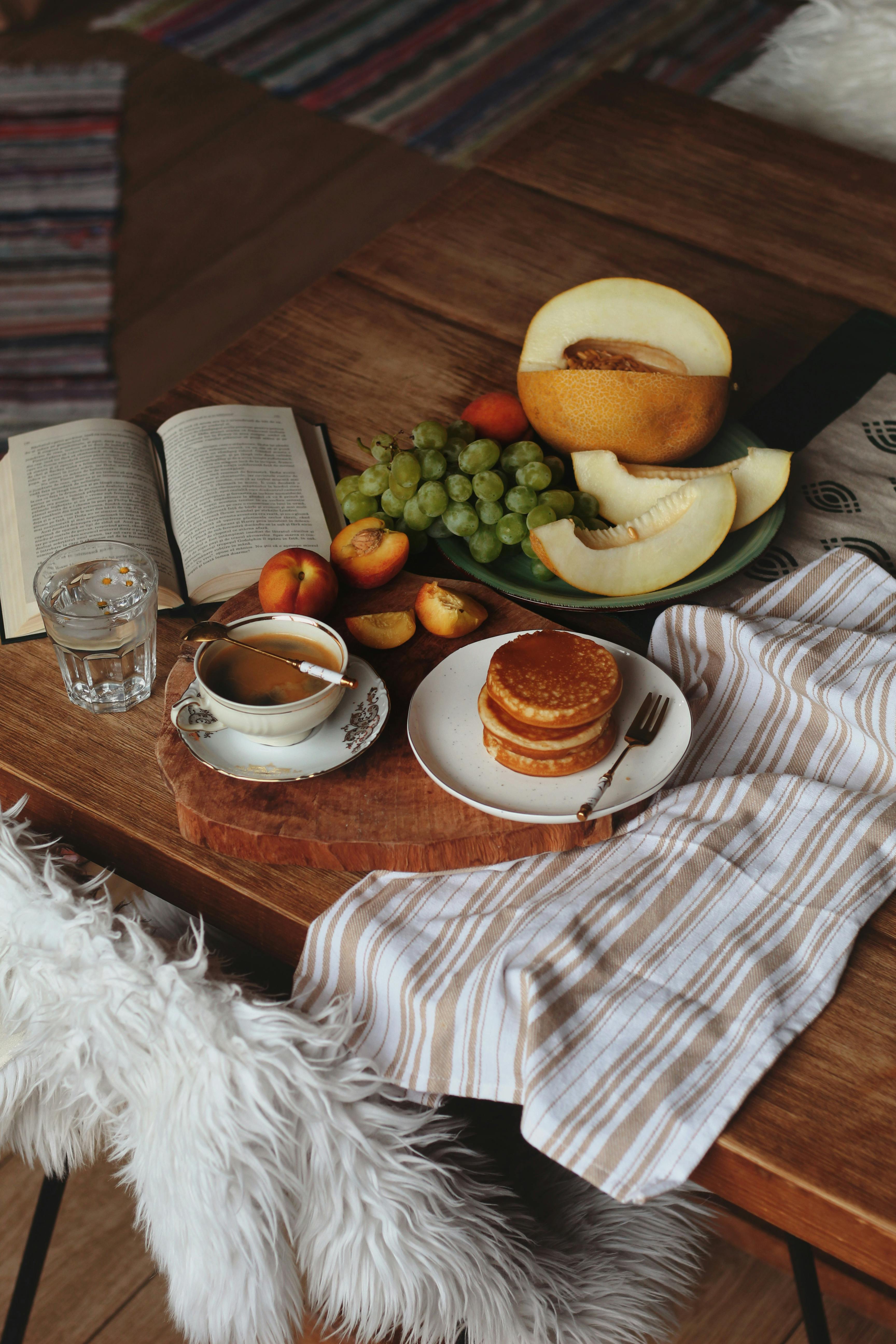 Inviting breakfast table with pancakes, fruits, and a cup of coffee in a cozy home setting.