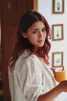 Young woman in a relaxed setting holding a warm cup of coffee indoors.