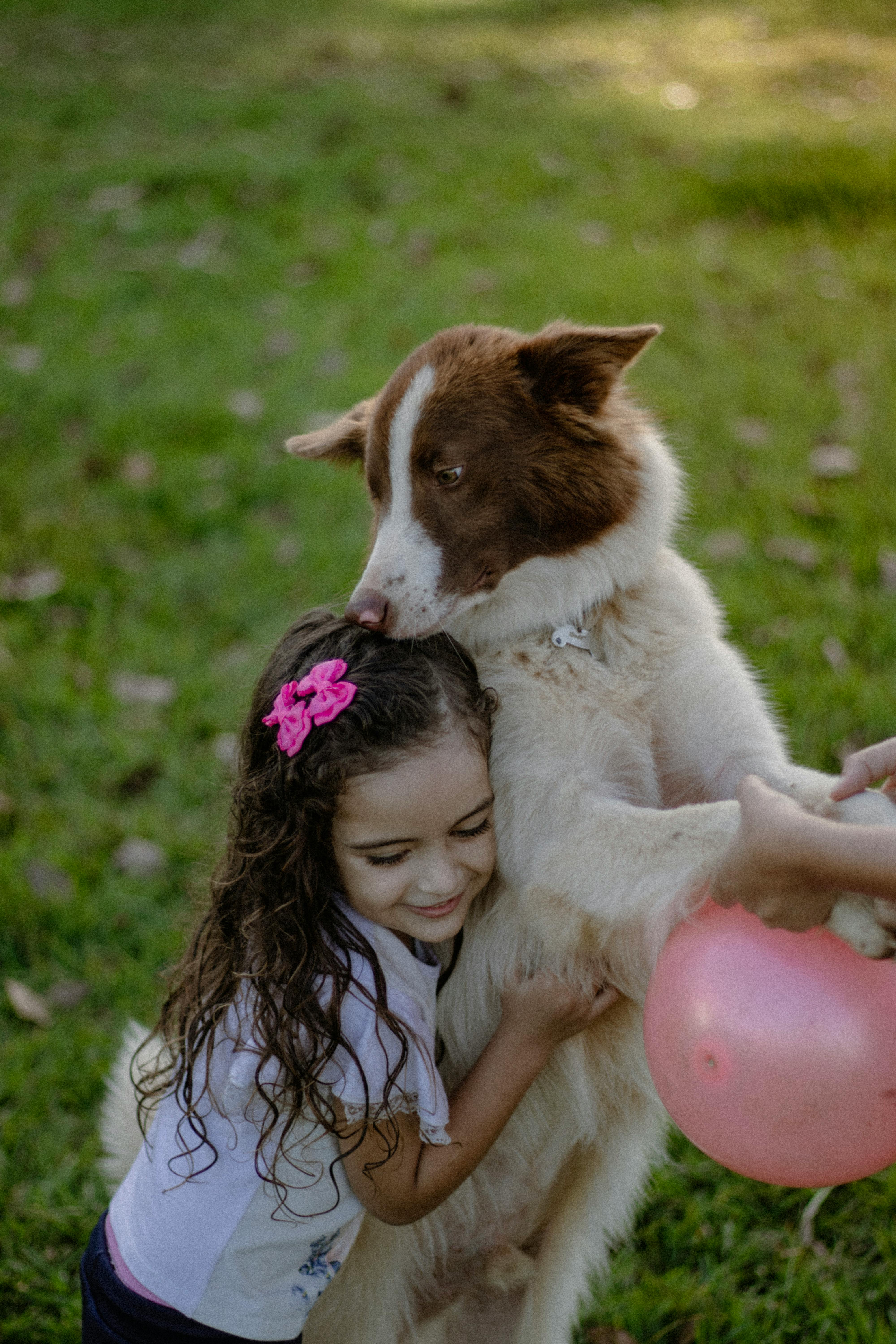 a kid in a white shirt hugging a dog