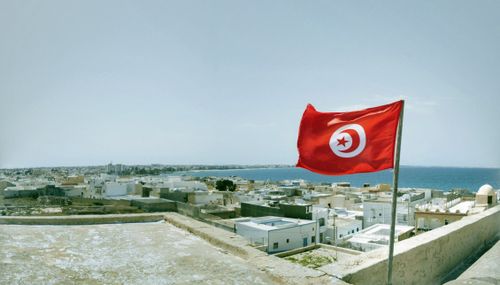 Free A vibrant Tunisian flag waving over the coastal town of Mahdia with a waterfront view. Stock Photo