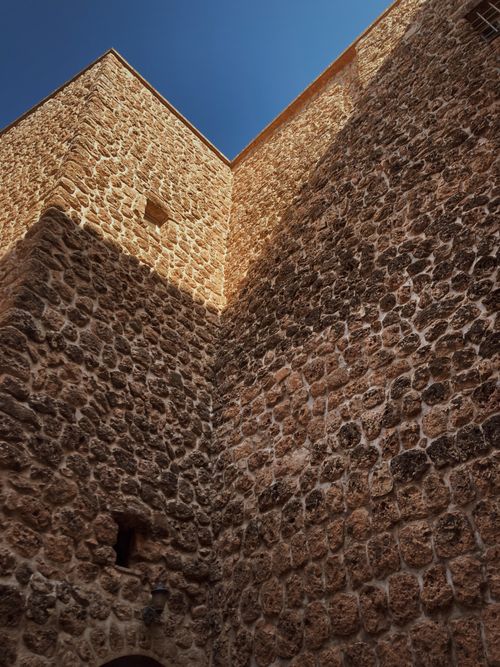 Free Low angle shot of an ancient stone facade under a clear blue sky highlighting texture and craftsmanship. Stock Photo