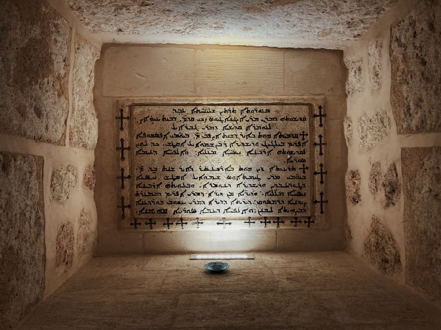 Detailed view of ancient Arabic script on a stone wall, illuminated in a museum setting.