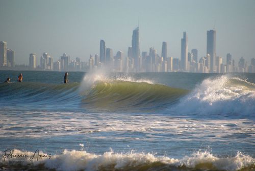 Free Surfers enjoy the waves at Gold Coast beach with the iconic skyline in the background. Stock Photo