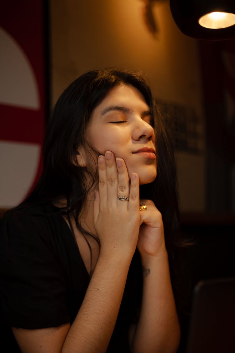 A Young Woman Closing Her Eyes In Black Shirt