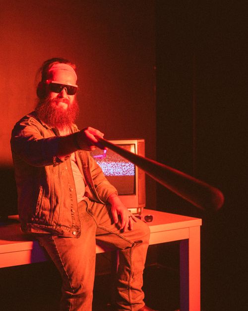 Free Stylish bearded man holding a baseball bat in a retro-themed room with vintage TV. Stock Photo