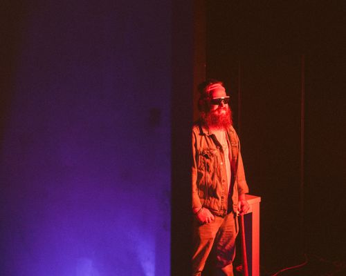 Free A bearded man wearing sunglasses stands in dramatic neon lighting, creating a modern and artistic scene. Stock Photo