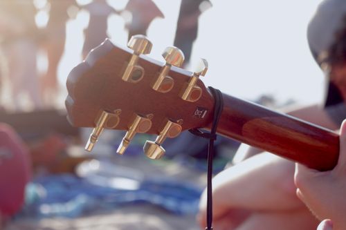 Free Guitar headstock with tuning pegs in focus at a sunny outdoor gathering. Stock Photo
