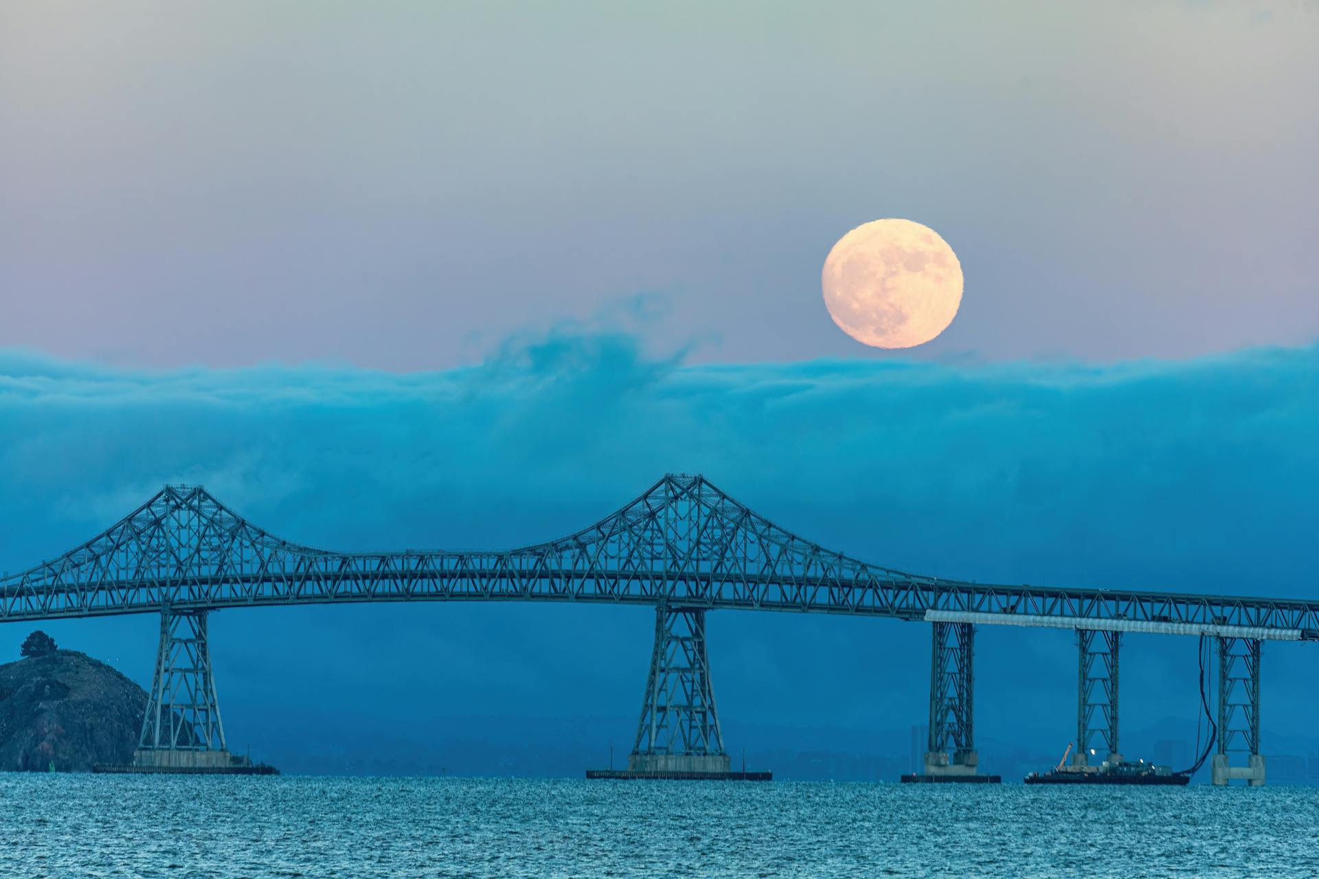 Majestic view of the Richmond San Rafael Bridge silhouetted against a supermoon over San Francisco Bay.