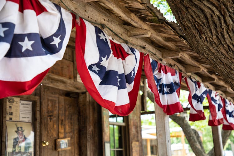 Flags Hanging On A Wire Near Wooden House