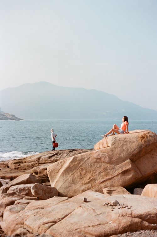 Free Two people enjoying a scenic day by the rocky Hong Kong coast with fishing and relaxation. Stock Photo