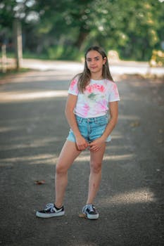 Youthful girl in denim shorts poses on a sunny day outdoors.