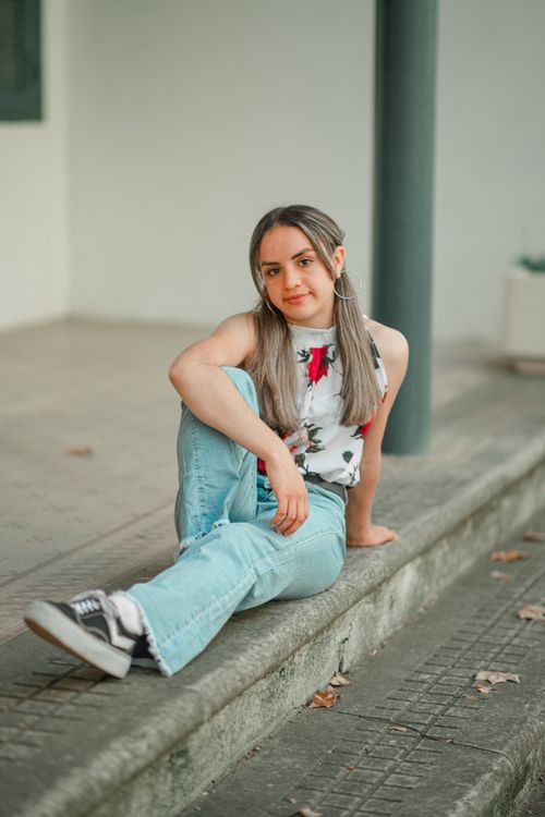 Free Young woman with blonde highlights sitting casually on steps outdoors, wearing casual attire. Stock Photo