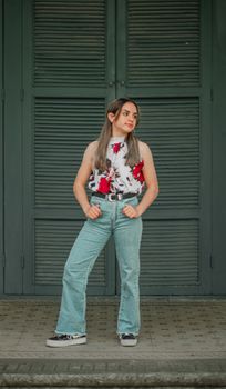 Stylish woman in floral blouse and jeans posing confidently outdoors.