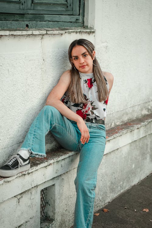 Woman in White Floral Top and Jeans Posing