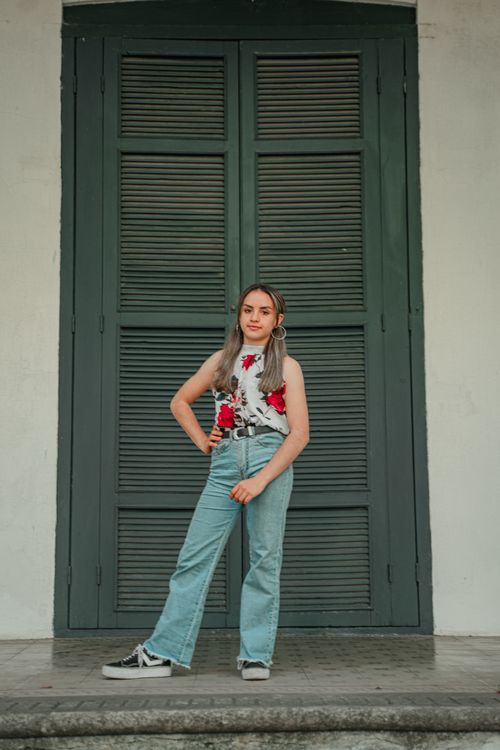 Free Confident young woman in denim and floral blouse posing outdoors with a vintage vibe. Stock Photo