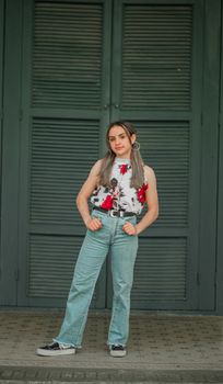 Fashionable young woman poses confidently against wooden doors in casual attire.
