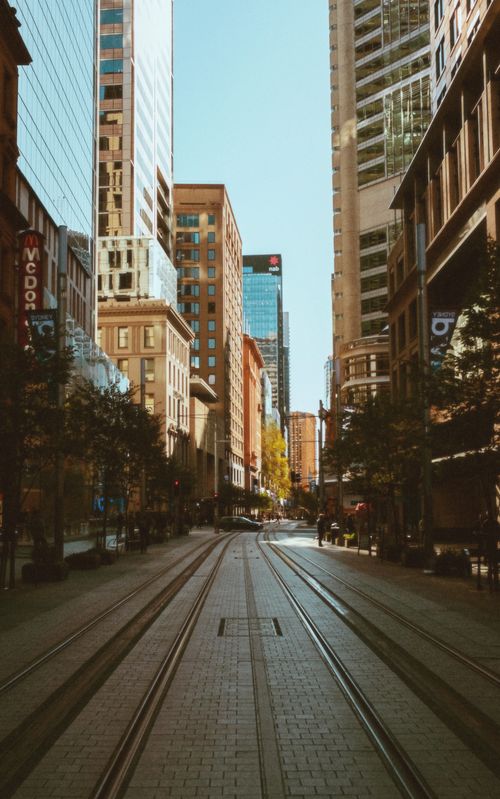 Free City street with skyscrapers and tram tracks, capturing urban life in daylight. Stock Photo