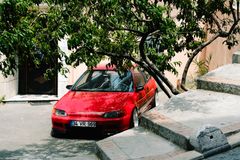 Red compact hatchback parked on a shaded street - photo by Mathias Reding on Pexels