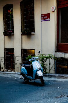 A vintage-style scooter parked on an urban street, set against a charming building facade.