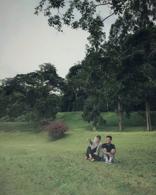 Happy Men Sitting on Grass under Trees