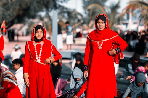 Teenagers Wearing Traditional Maldivian Red Dresses with Golden Trims and Hijabs