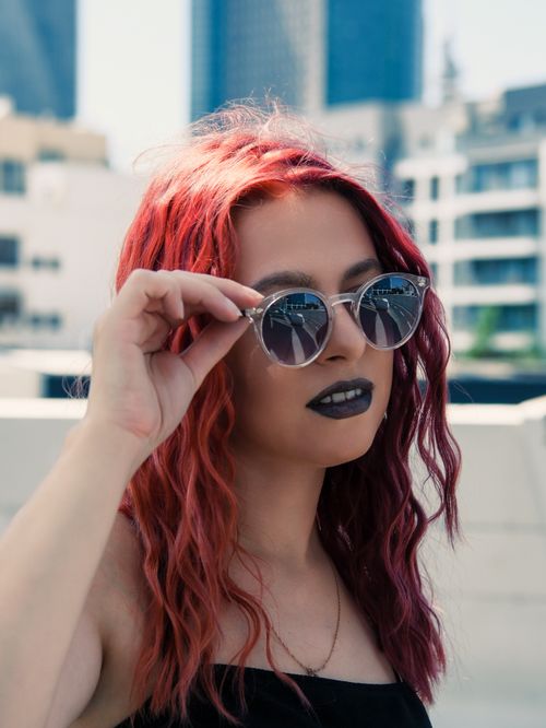 Free Stylish redhead woman with sunglasses posing on a sunny day in Tel Aviv. Stock Photo