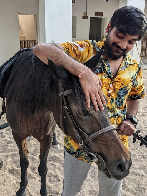 A Man in Printed Shirt Petting a Horse