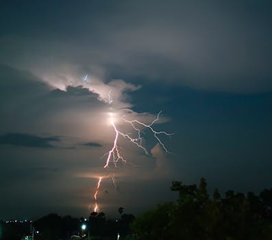 Captivating nighttime lightning storm over countryside, showcasing nature's power.