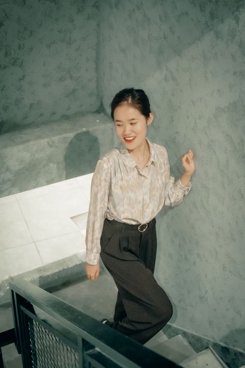 Free An Asian woman with brunette hair smiling while walking up a staircase indoors. Stock Photo