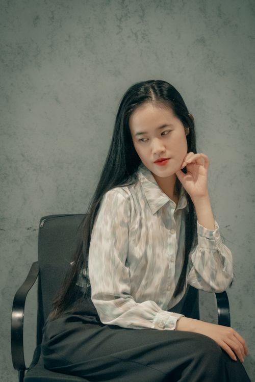 Free A contemplative Asian woman in stylish attire looks sideways indoors, exuding elegance. Stock Photo