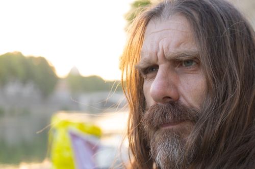 Free Intense close-up portrait of a long-haired bearded man with a thoughtful expression outdoors. Stock Photo