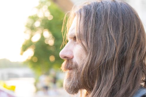 Free Side profile portrait of a bearded man with long hair in natural outdoor setting. Stock Photo