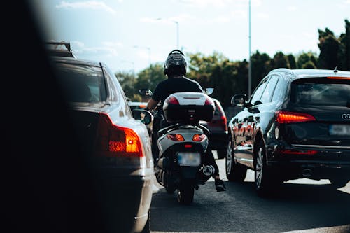 Photo of a Motorcycle Driving between Cars in Traffic Jam