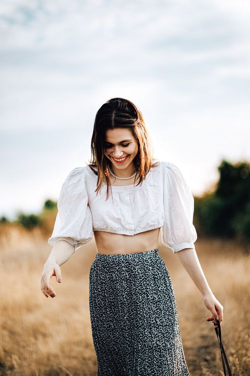 Free Smiling woman in a white blouse walking outdoors on a sunny day. Stock Photo