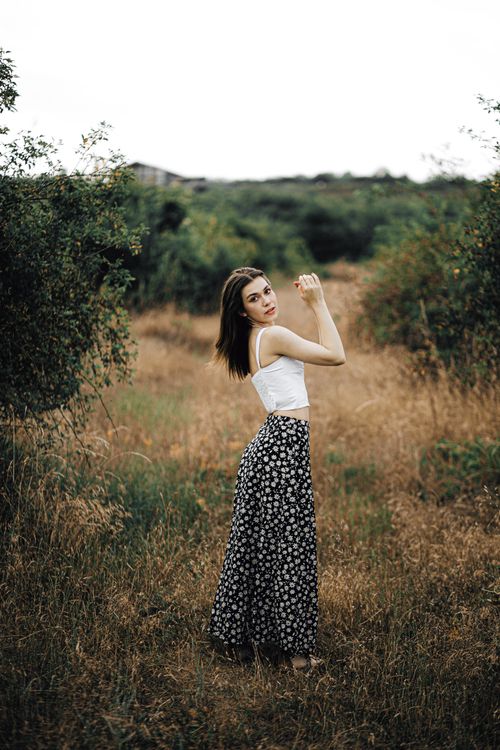 Free A fashionable young woman in a floral skirt posing in a rural summer setting. Stock Photo