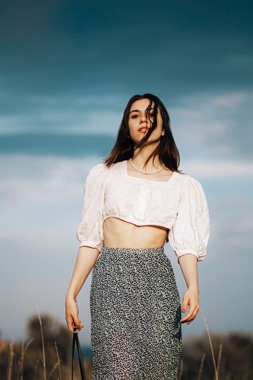 Free Stylish young woman in puff sleeve blouse and long skirt posing outdoors. Stock Photo