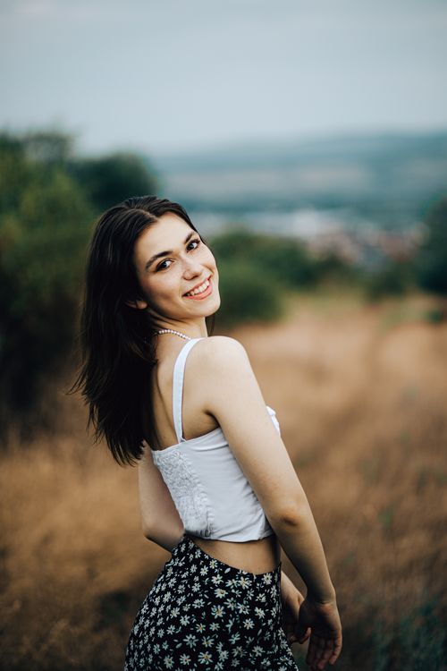 Free Portrait of a smiling woman in a floral skirt, outdoors in the countryside. Stock Photo