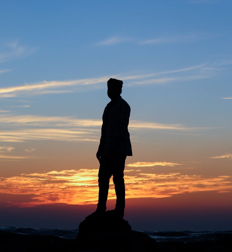 Silhouette Of A Man Standing On A Rock