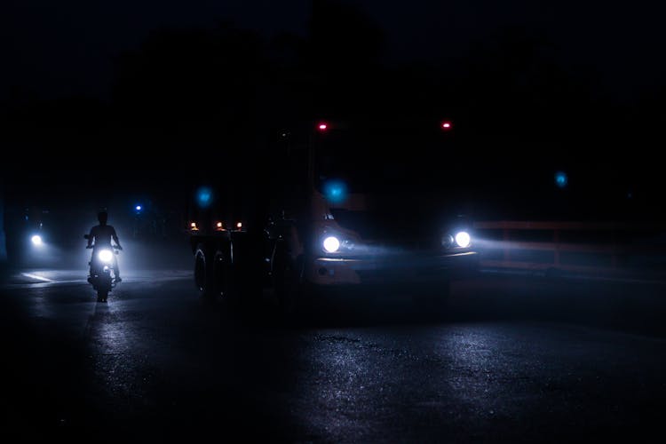 Photo Of A Truck, A Car And A Motorcycle Driving With Lights On A Road At Night