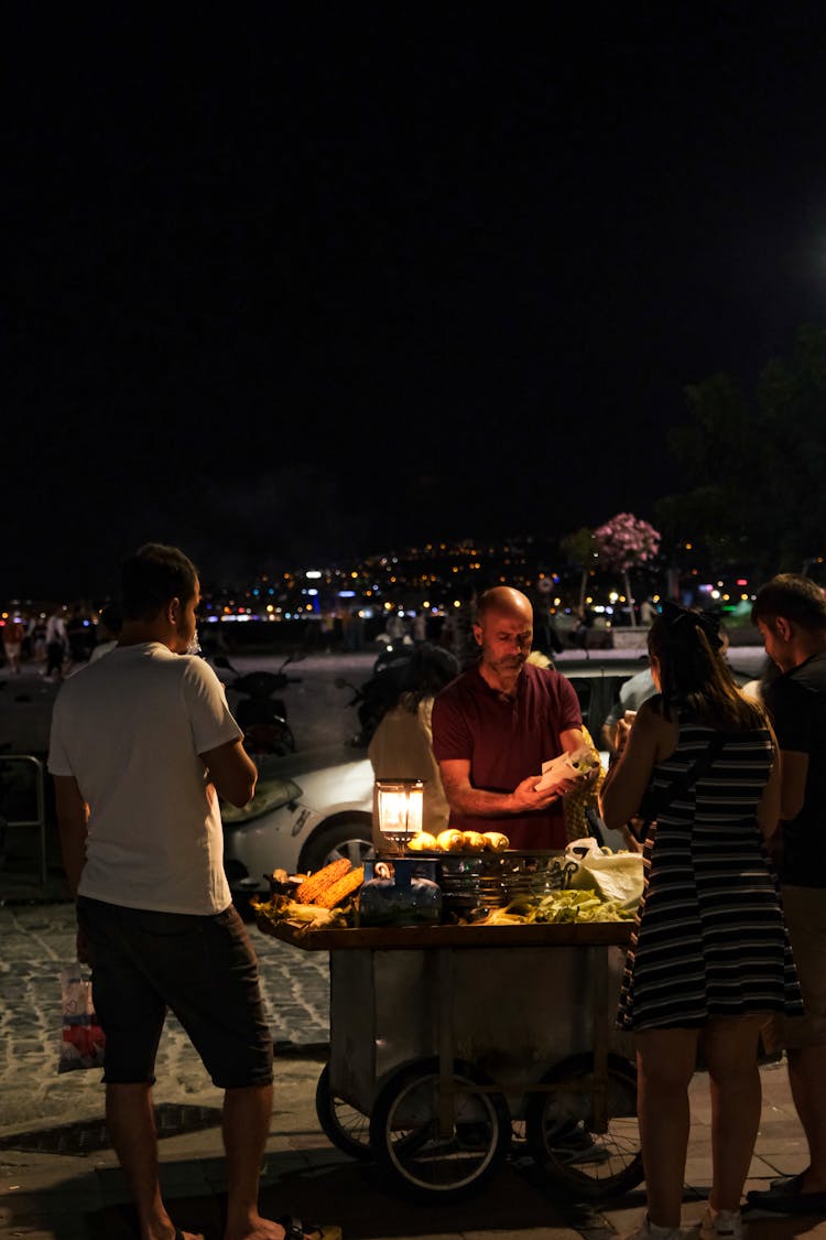 People Buying Food At At Street Stall At Beach At Night